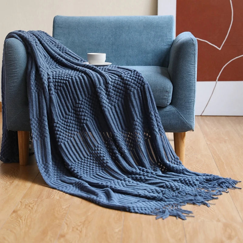 Blue textured blanket draped over a blue armchair with a white cup on a wooden floor.