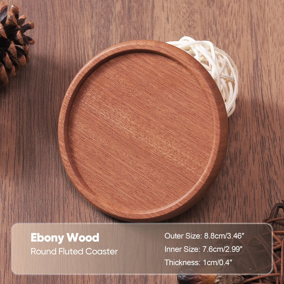 Round fluted coaster made of ebony wood on a wooden surface with text detailing its dimensions.