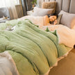 Woman lying on a bed with a green comforter in a cozy bedroom.