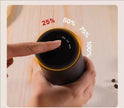 Hand holding a coffee cup with a digital display showing percentage levels on a wooden surface.