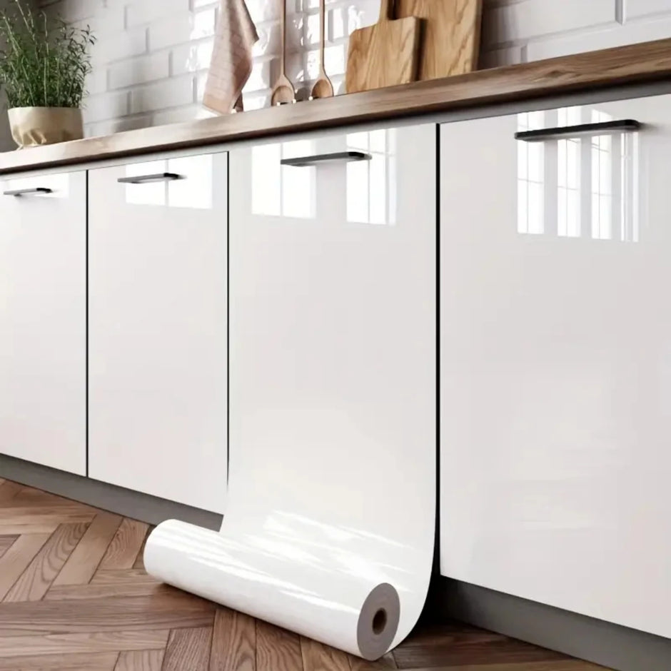 Roll of paper on a wooden floor with white cabinets and a tiled wall in the background