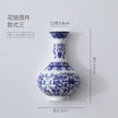 Blue and white ceramic vase with floral patterns and dimensions on a light gray background