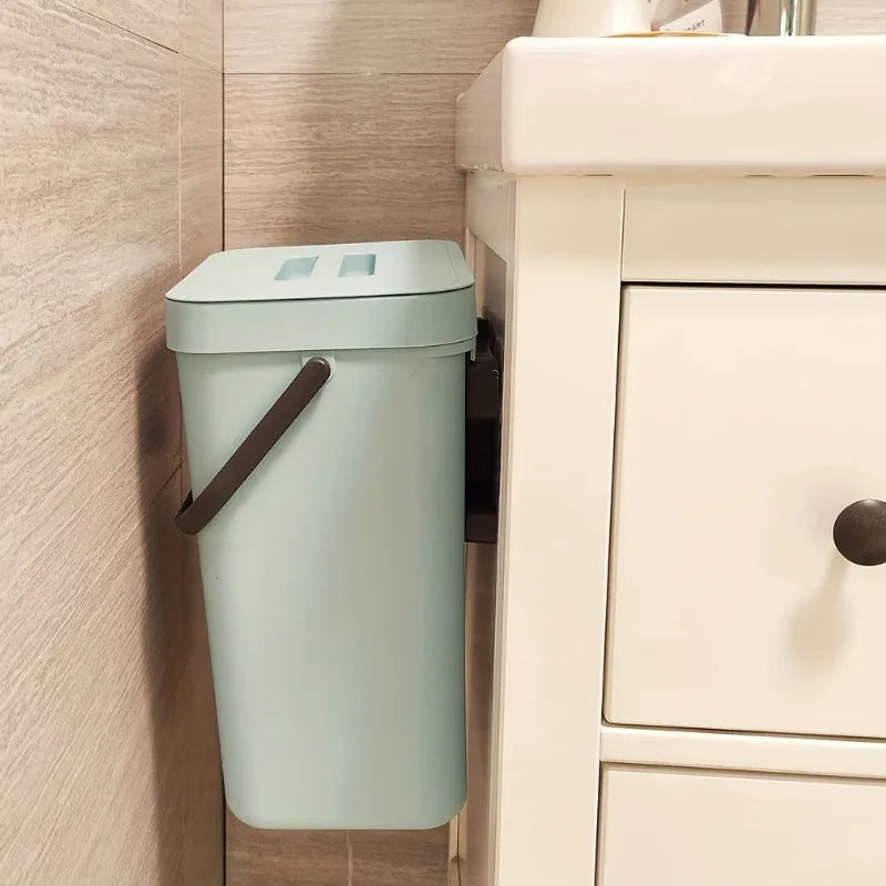 Green trash can attached to a wall in a bathroom setting