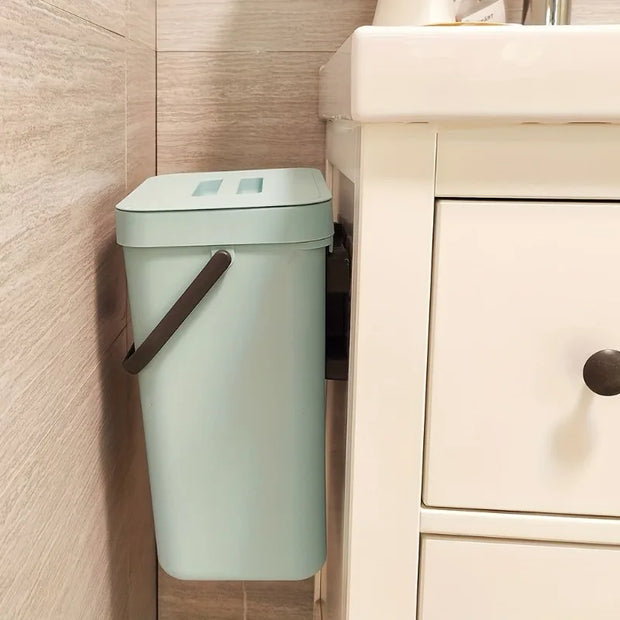 Green trash can attached to a wall in a bathroom setting
