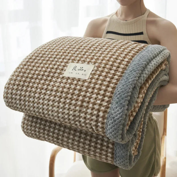 Person holding a folded blanket with a brand label against a white background