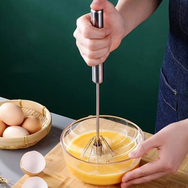 Person whisking eggs in a glass bowl with a hand mixer on a wooden cutting board.