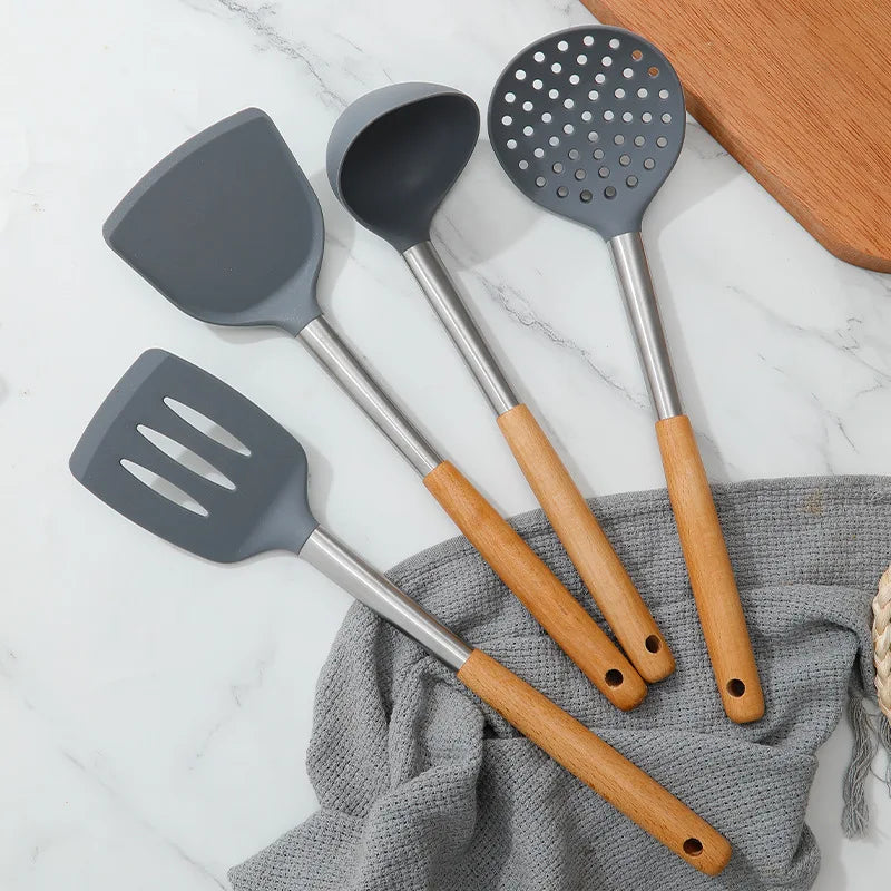 Set of gray kitchen utensils with wooden handles on a marble surface