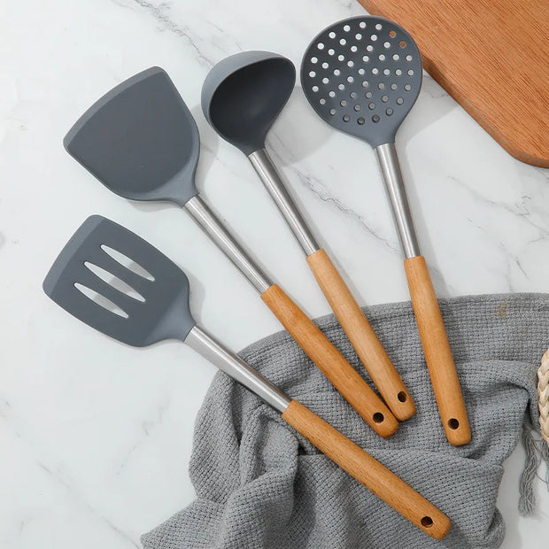 Set of gray kitchen utensils with wooden handles on a marble surface