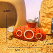 Small red submarine toy with measurements on a sandy surface