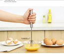 Hand using a whisk to mix eggs in a bowl on a kitchen counter.