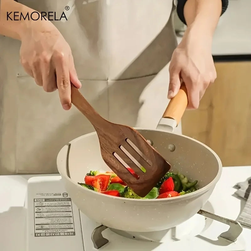 Person using a wooden spatula to stir vegetables in a KEMORELA frying pan.