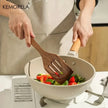 Person using a wooden spatula to stir vegetables in a KEMORELA frying pan.