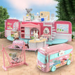 Toy camper with various rooms and a toy bus on a wooden floor.