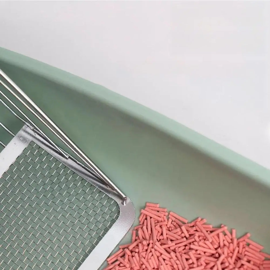 Green scoop with pink cat litter on a white background