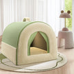 Green and beige pet house on a wooden floor with a soft rug and a pink cushioned stool in the background.