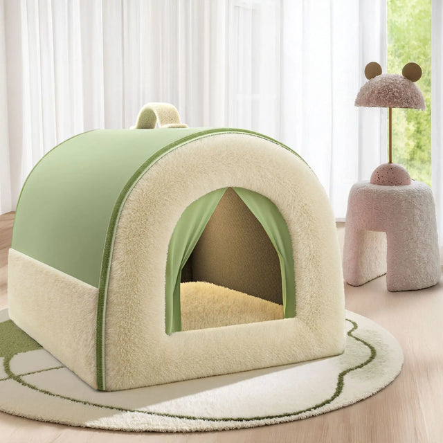 Green and beige pet house on a wooden floor with a soft rug and a pink cushioned stool in the background.