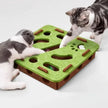 Two cats playing with a green and brown puzzle toy on a white surface