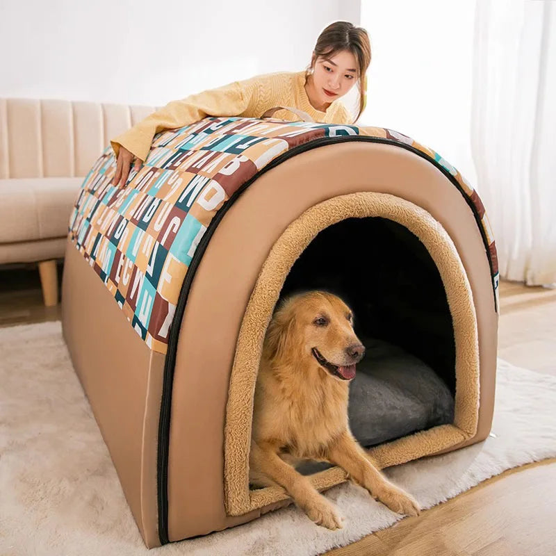 Dog lying in a beige pet bed with a colorful blanket, next to a person on a couch.