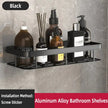 Black aluminum alloy bathroom shelf with various bottles on a gray tiled wall.