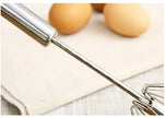 Metal whisk with eggs on a light background