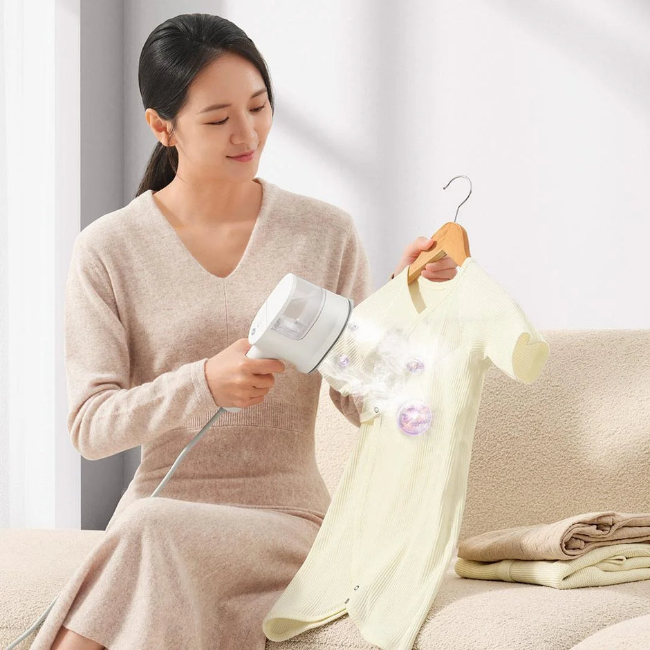 Woman using a handheld steamer on a garment in a home setting