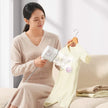 Woman using a handheld steamer on a garment in a home setting