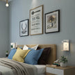 Bedroom with a bed featuring colorful pillows, framed artwork on the wall, and nightstands with lamps.