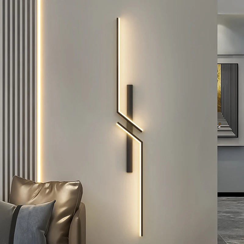 Modern wall light fixture on a neutral wall with a couch and decorative pillows in the foreground.