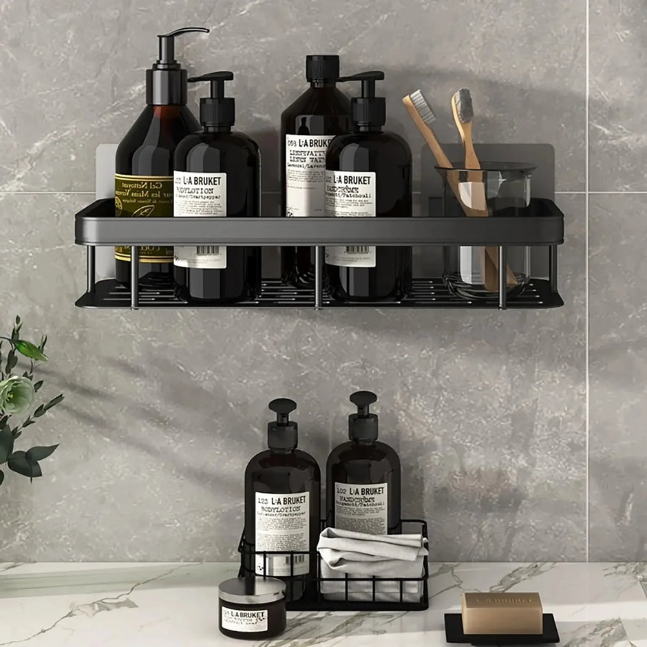 Bathroom shelf with various bottles and toiletries against a gray tiled wall.
