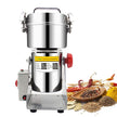 Stainless steel grain grinder with spices and herbs on a white background