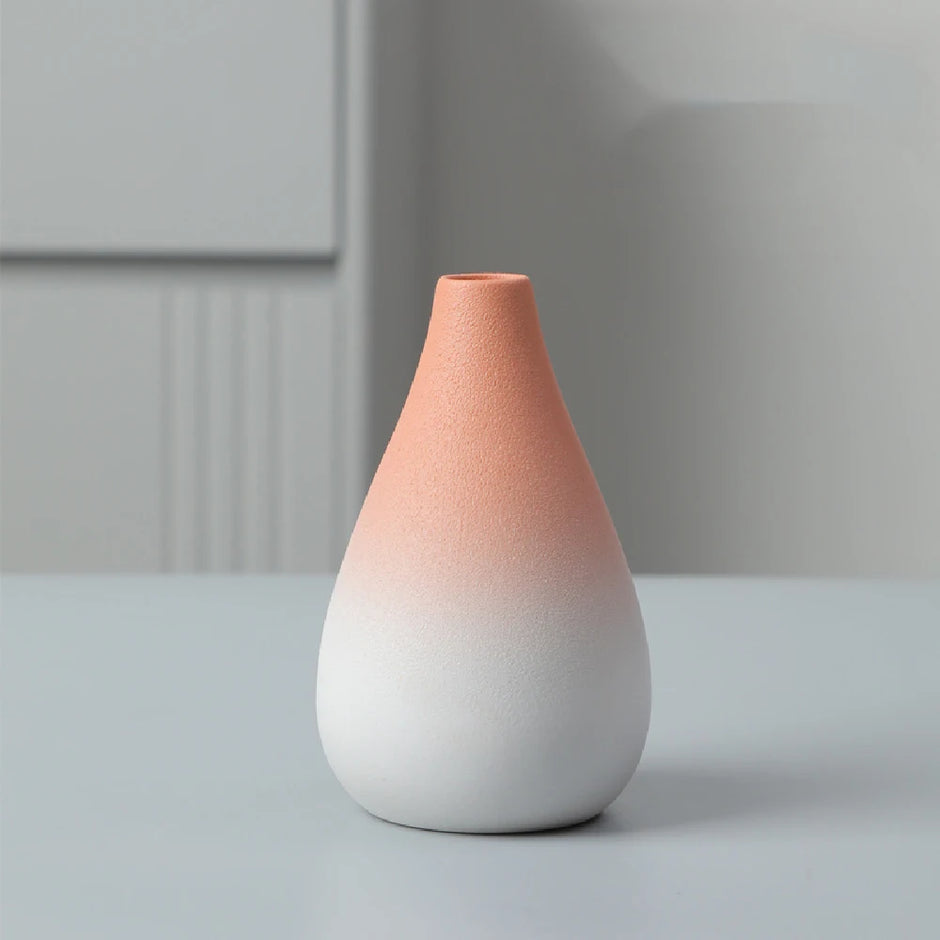 Gradient ceramic vase transitioning from pink to white on a light gray surface with a neutral background