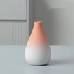 Gradient ceramic vase transitioning from pink to white on a light gray surface with a neutral background