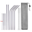 Set of metal straws with cleaning brush and mesh pouch on a white background