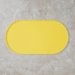 Yellow bath mat on a gray tiled floor