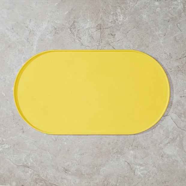 Yellow bath mat on a gray tiled floor