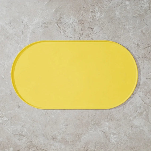 Yellow bath mat on a gray tiled floor