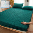Green quilted mattress cover on a bed with a close-up inset showing water resistance.