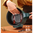 Person cleaning a green pot with a black interior on a wooden surface.