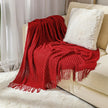 Red knitted blanket draped over a beige sofa with a white pillow.