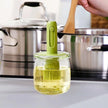 Green oil brush with a container of oil on a kitchen counter