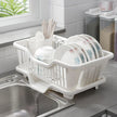 White dish rack with dishes on a kitchen counter next to a sink