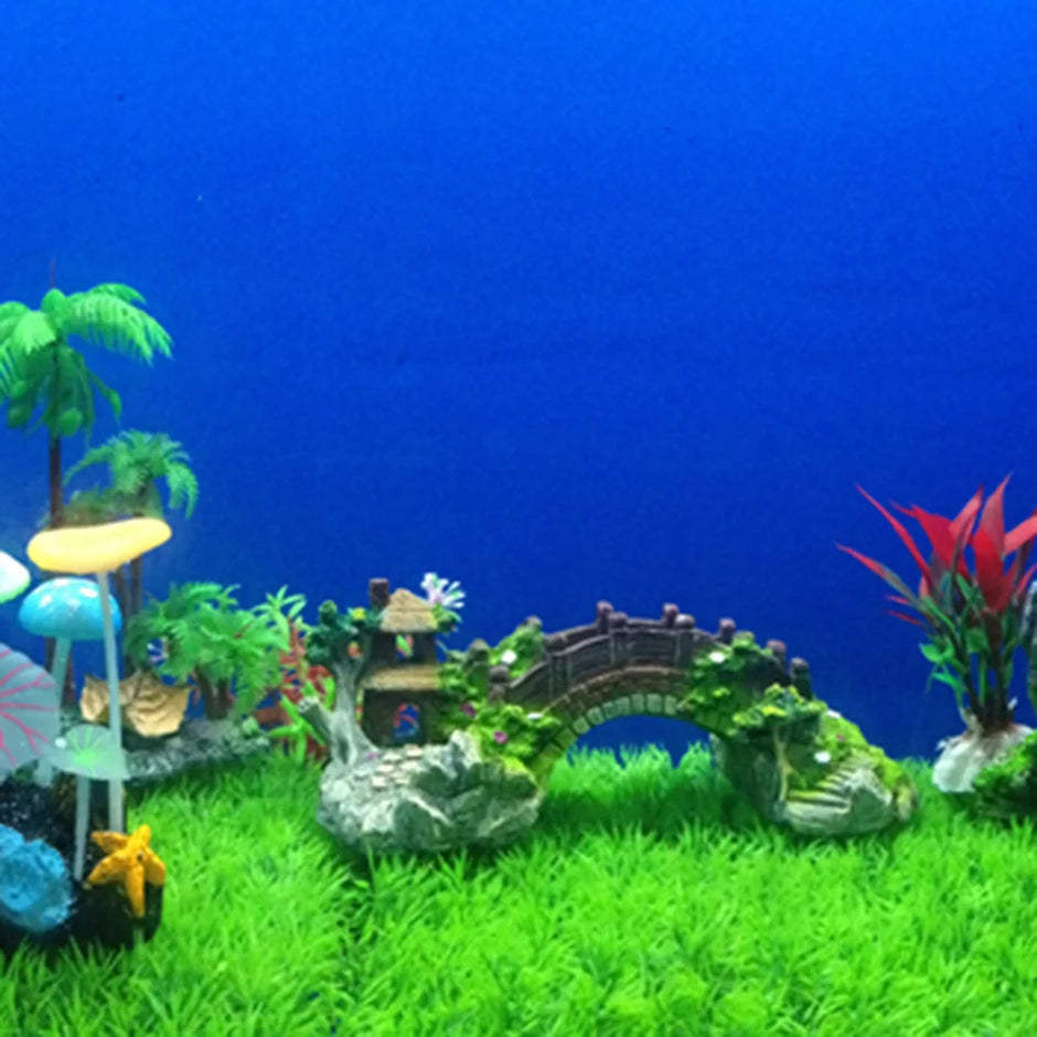 Aquarium decoration with a small bridge, plants, and fish on a blue background