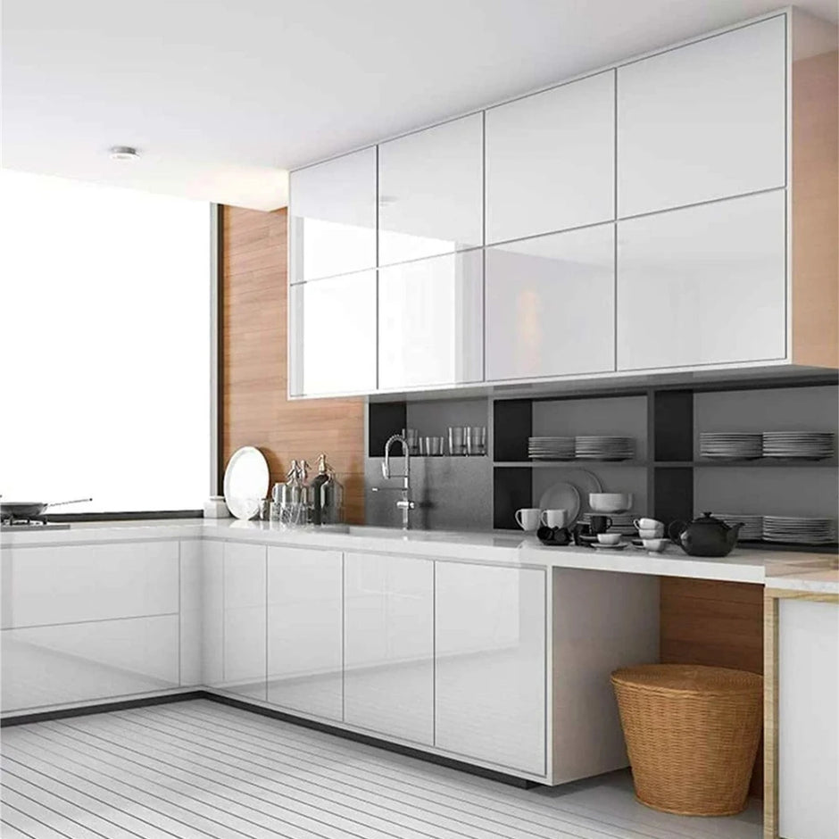 Modern kitchen with white cabinets, wooden accents, and a countertop with various items.