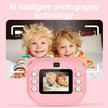 Pink children's camera with two children posing behind it on a pink background