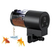 Black fish feeder dispensing food with goldfish nearby on a white background