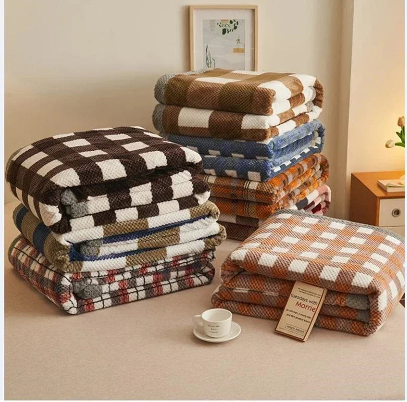 Stacks of plaid blankets on a bed with a tag displaying the brand name.