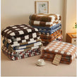 Stacks of plaid blankets on a bed with a tag displaying the brand name.