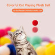 Cat playing with colorful plush balls on a light pink background