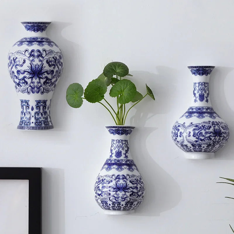 Blue and white patterned vases on a white wall with a plant in the center.