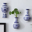 Blue and white patterned vases on a white wall with a plant in the center.